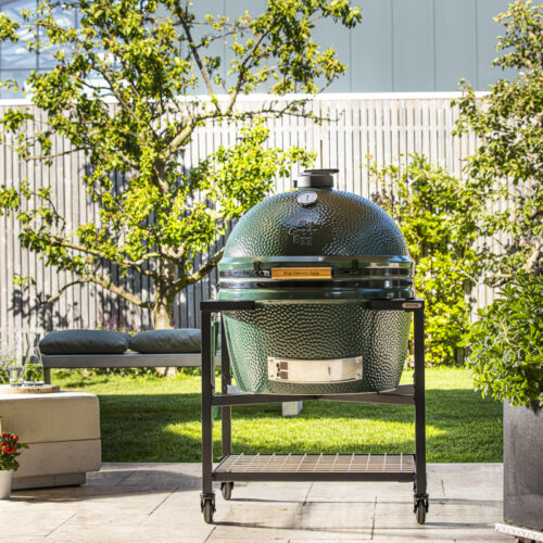 Big Green Egg Kamado-Grill auf fahrbarem Untergestell in einem modernen Gartenambiente.