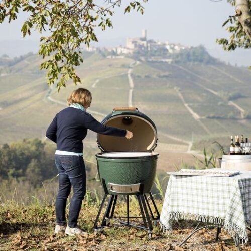 Person grillt mit einem Big Green Egg in malerischer Landschaft mit Blick auf die Weinberge.